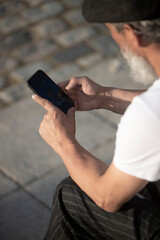 older man's hands outdoors with cell phone