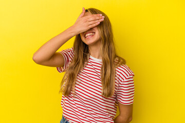Young blonde caucasian woman isolated on yellow background laughs joyfully keeping hands on head. Happiness concept.