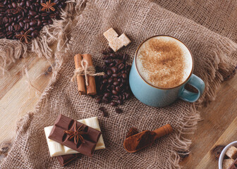 cup of coffee, chocolate, beans, anise and cinnamon on wooden background