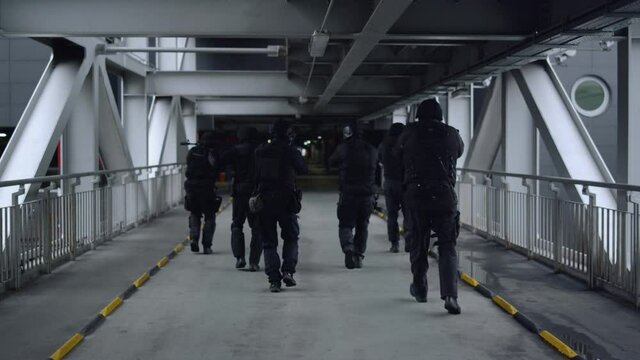 Special ops police squad with sniping rifles inspecting construction bridge