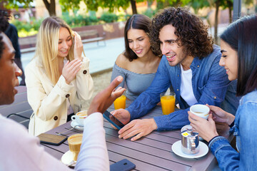 Multi-ethnic group of friends having a drink together in an outdoor bar.
