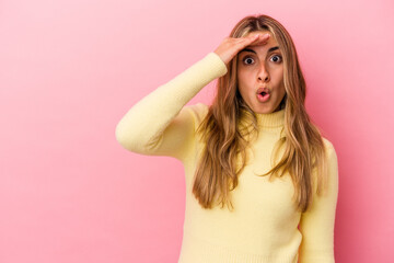 Young blonde caucasian woman isolated on pink background looking far away keeping hand on forehead.