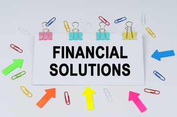 On the table there are paper clips and directional arrows, a sign that says - FINANCIAL SOLUTIONS