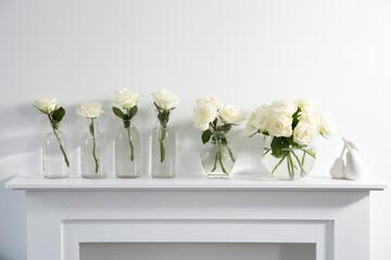 Bouquet of white roses in a glass figured vase on a white fireplace console.