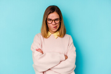 Young student caucasian woman isolated on blue background frowning face in displeasure, keeps arms...