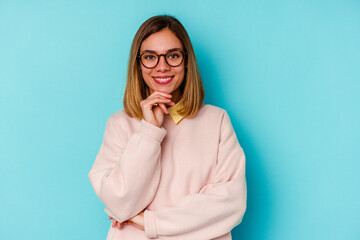 Young student caucasian woman isolated on blue background smiling happy and confident, touching chin with hand.