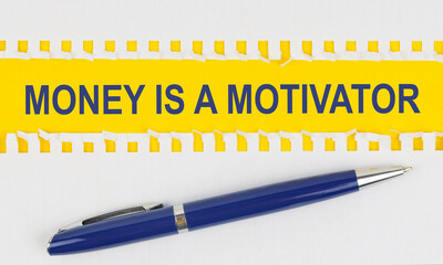 On the table are two sheets from a notebook and a pen on a yellow background written - MONEY IS A MOTIVATOR