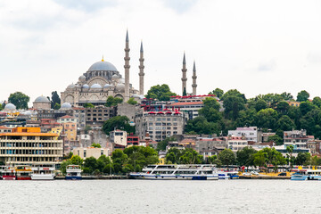 Naklejka premium Istanbul cityscape with boats and Suleymaniye Mosque (Ottoman imperial mosque). Old town with colored buildings. Eminonu Ferryboat docks facing the mouth of the Golden Horn Bay.View from Galata bridge