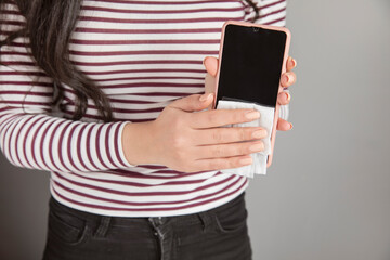 Woman cleaning phone with antiseptic wipe