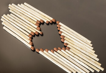 Matches formed as a heart on dark grey background. Matchsticks in the shape of a heart. Conceptual image.