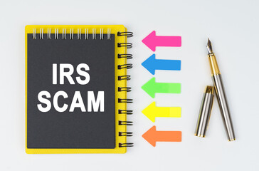 On a white background lies a pen, arrows and a notebook with the inscription - IRS SCAM