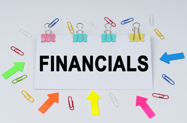 On the table there are paper clips and directional arrows, a sign that says - FINANCIALS