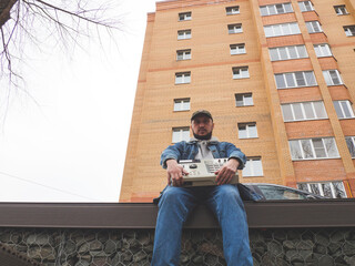 A hip hop beatmaker in the park holds an old-school ' 90s drum machine in his hands . Retro Digital...