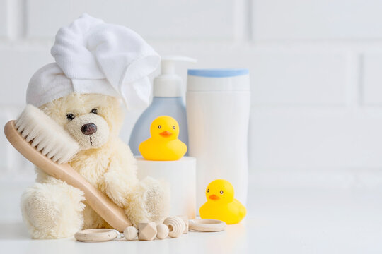 Baby bath accessories, baby care, a yellow bear with a towel on its head, a brush and bottles of shampoo.