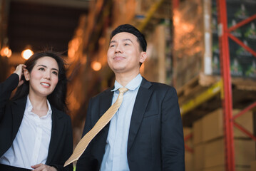 Portrait Young Asian man and woman owner manager stand talking near shelf product box in big warehouse factory store which smile and felling happy, logistic import and export transportation concept