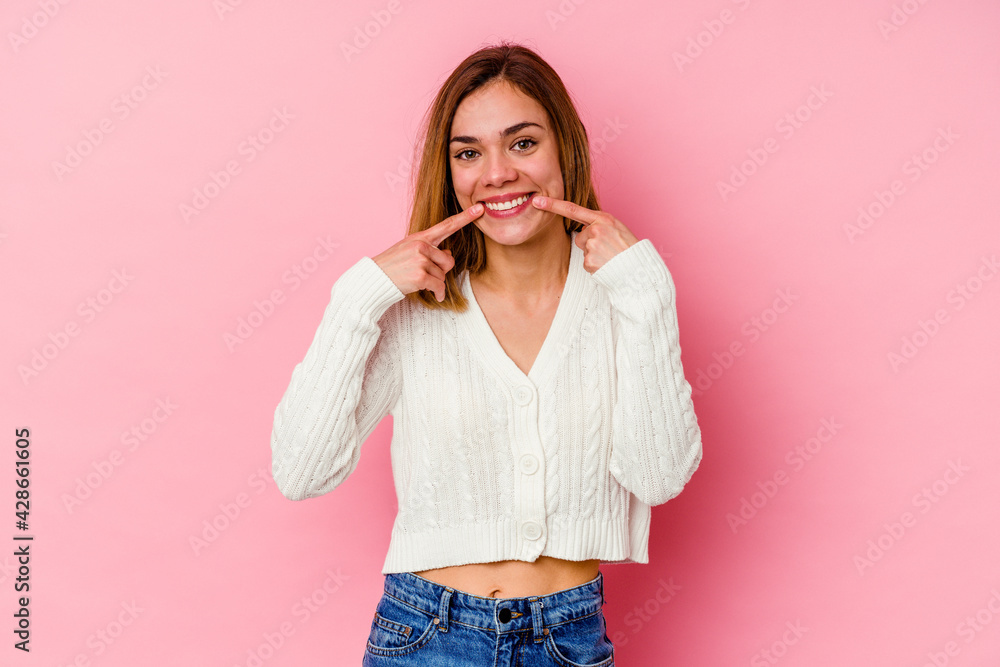 Sticker Young caucasian woman isolated on pink background smiles, pointing fingers at mouth.