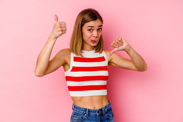 Young caucasian woman isolated on pink background showing thumbs up and thumbs down, difficult choose concept