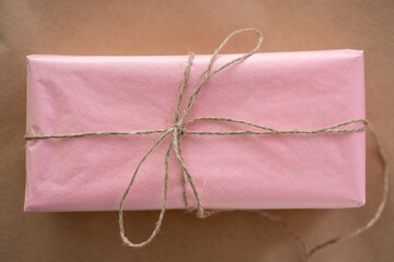 pink gift in craft rope on white background