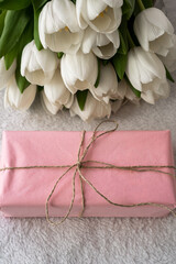 white tulips and pink gift in craft rope on white background