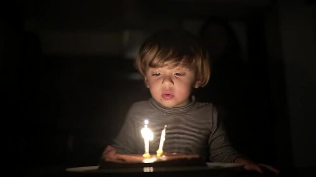 Baby toddler celebrating birthday, child blowing cake candles in slow-motion