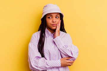 Young african american woman isolated on yellow background contemplating, planning a strategy, thinking about the way of a business.