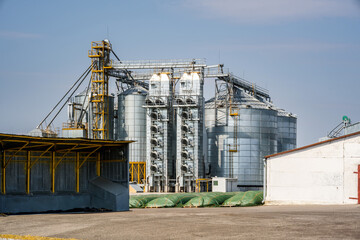 Fototapeta premium Modern Granary elevator. Silver silos on agro-processing and manufacturing plant for processing drying cleaning and storage of agricultural products, flour, cereals and grain. seed cleaning line