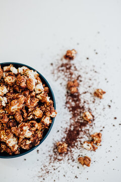 confectioner, sweet popcorn in a caramel in a black plate on a white background