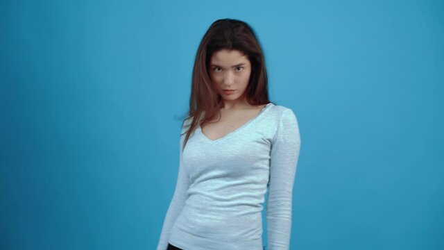 The insecure and confused girl displays an unresolved problem by using her hand as a pistol with which she shoots herself in the head. Asian with dark hair, dressed in a blue blouse, isolated on a