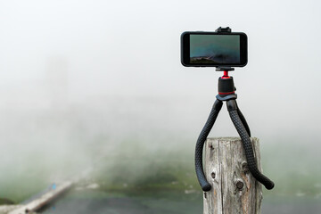 Smartphone on the tripod taking photos. Capturing image or time lapse of moving clouds in the...