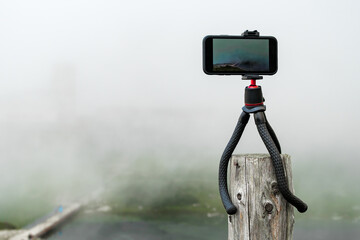 Smartphone on the tripod taking photos. Capturing image or time lapse of moving clouds in the mountains. Device for blogging 