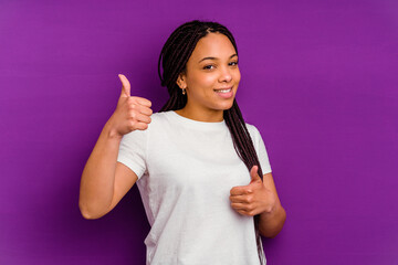 Young african american woman isolated on yellow background raising both thumbs up, smiling and confident.