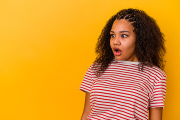 Young african american woman isolated on yellow background being shocked because of something she has seen.