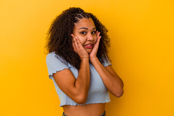 Young african american woman isolated on yellow background scared and afraid.