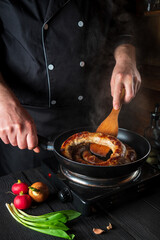 Cooking meat sausage in the restaurant kitchen. The chef fries sausage in frying pan. The idea of a delicious meat dish