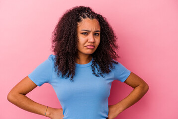 Young african american woman isolated on pink background blows cheeks, has tired expression. Facial...