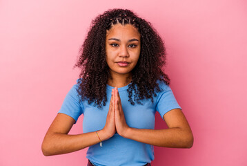 Young african american woman isolated on pink background praying, showing devotion, religious...