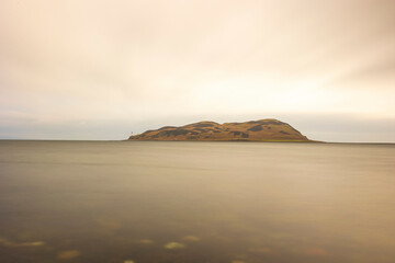 Long exposure horizontal photo, sea horizon, small island with a lighthouse.