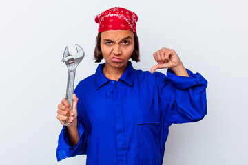 Young mechanical woman holding a key isolated showing a dislike gesture, thumbs down. Disagreement concept.