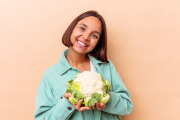 Young mixed race woman holding a cabbage isolated on beige background