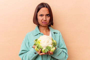 Young mixed race woman holding a cabbage isolated on beige background