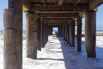 Waves hitting an old pier on a sunny day.