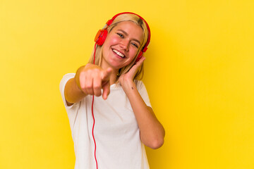 Young venezuelan woman listening music isolated on yellow background