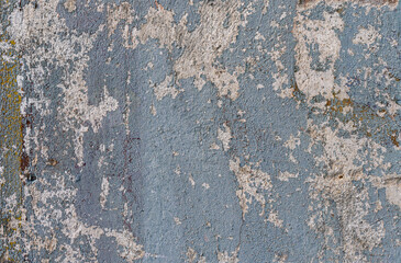 An old wall with remnants of plaster and cracked paint from time to time in different colors as a...