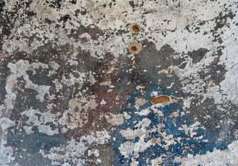 An old wall with remnants of plaster and cracked paint from time to time in different colors as a...