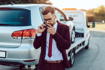 Elegant middle age business man calling towing service for help on the road. Roadside assistance...