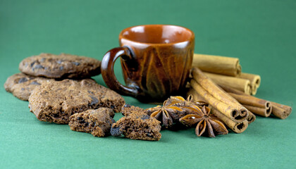image of a cup with coffee, chocolate chip cookies, anise, cinnamon on a green background