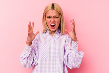 Young venezuelan woman isolated on pink background screaming with rage.