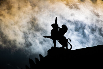 Griffin statue silhouette featuring statue, clouds, and sky