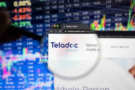 Teladoc company logo on a website with blurry stock market developments in the background, seen on a computer screen through a magnifying glass