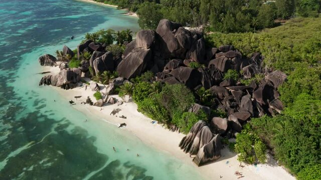 Amazing summer sun drone shot of La Digue island, Seychelles. Anse source D&rsquo;argent beach in paradise holiday vacation honeymoon hotspot. White sand beach with coconut palm trees and granite rocks.